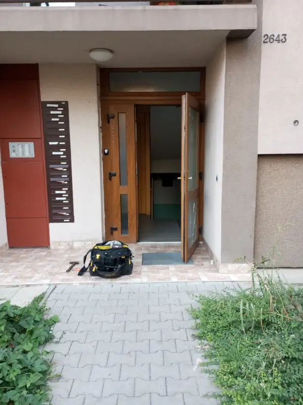 Vchod do bytového domu s nářadím před dveřmi